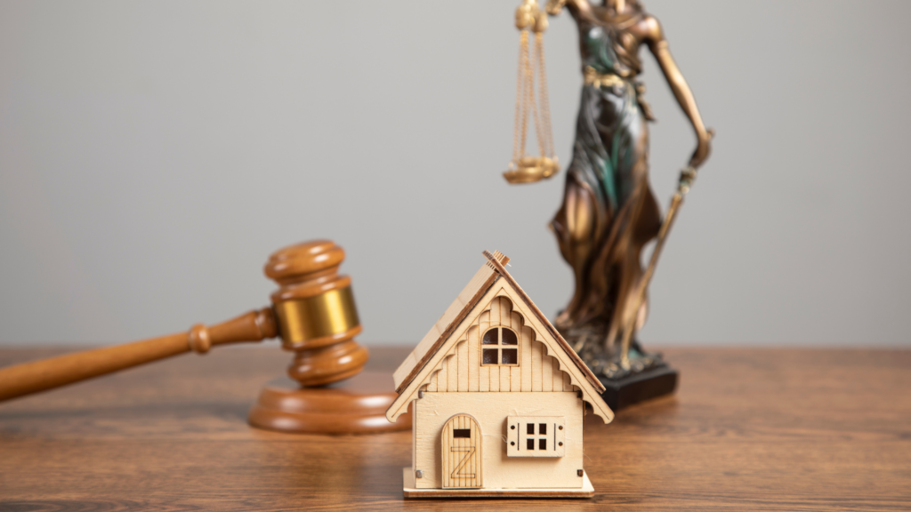 A miniature house and a gavel on a table