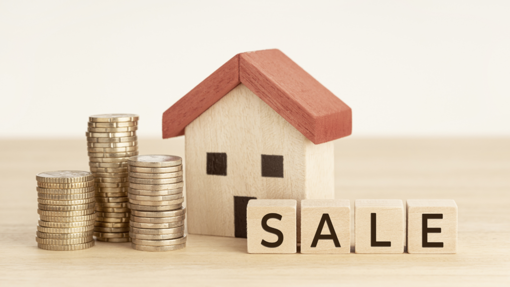 Coins, miniature house, and scrabble tiles arranged as SALE